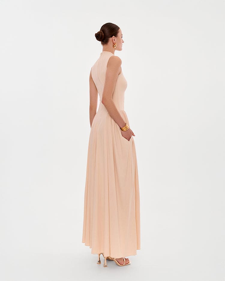 Nude sleeveless mock neck dress with a pleated maxi skirt